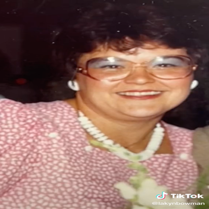 Lakyn's grandma smiles in a photo from years ago, wearing large glasses, bright makeup, and a patterned dress