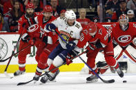 Florida Panthers' Aleksander Barkov (16) tries to get control of the puck between Carolina Hurricanes' Jordan Staal, left, and Martin Necas (88) during the second period of Game 2 of the NHL hockey Stanley Cup Eastern Conference finals in Raleigh, N.C., Saturday, May 20, 2023. (AP Photo/Karl B DeBlaker)