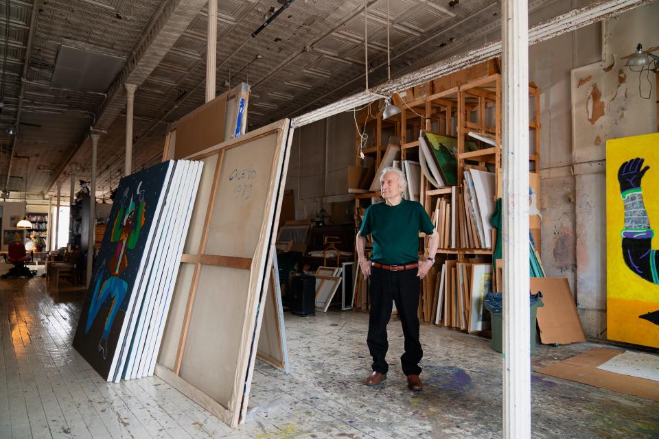 Carmen Cicero stands among giant paintings stacked up against a pole in his raw industrial loft space.