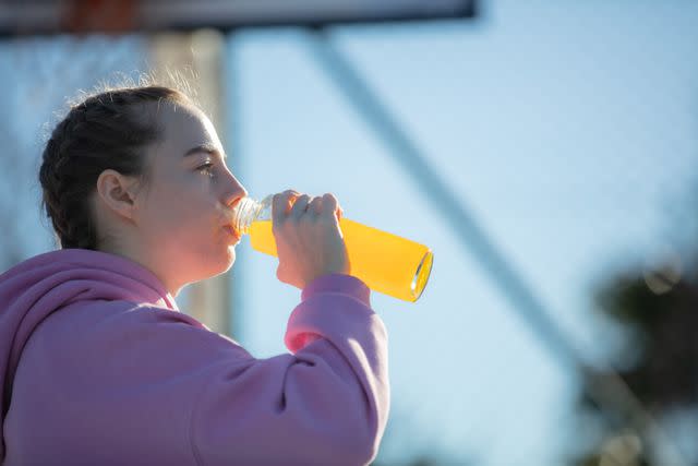 <p>Berk Ucak</p> A young individual with braids hydrating during exercise.