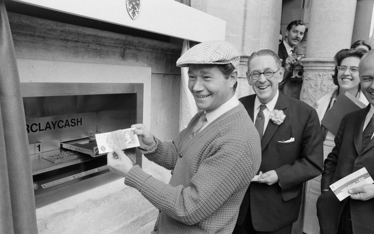 Comedian Reg Varney examines a bank note as he officially opens the world's first ATM in June 1967 - Mirrorpix