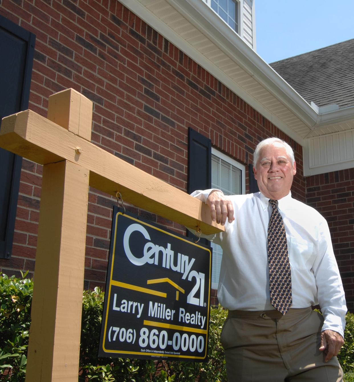 Larry Miller stands next to one of his familiar Century 21 real-estate signs in this photo from 2008. Miller died Sept. 13 at age 77.
