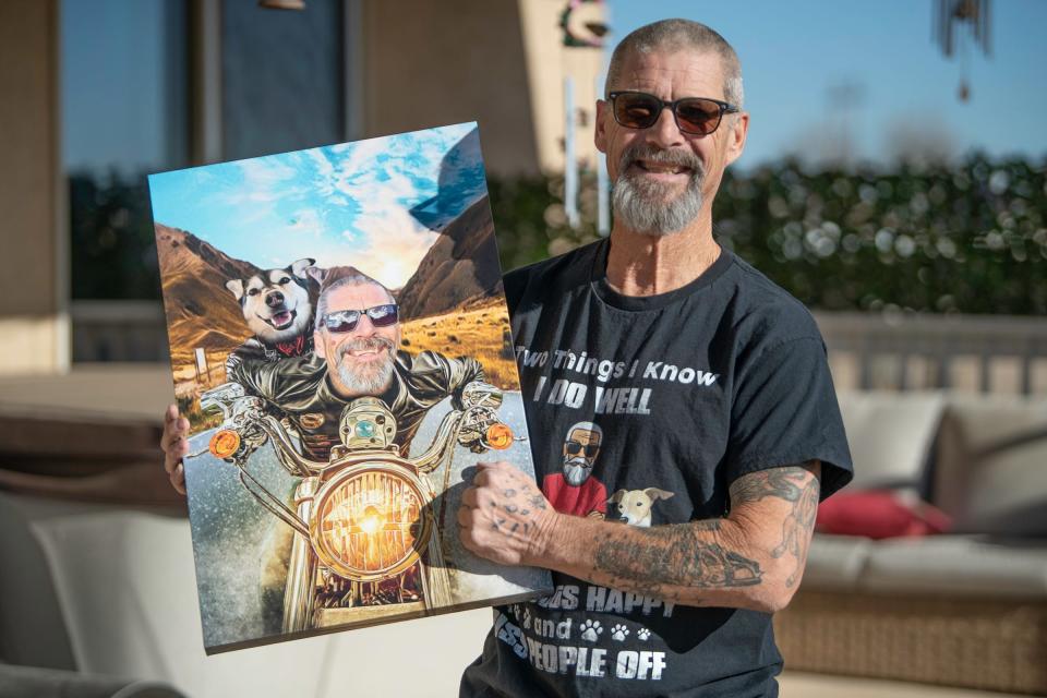 Kevin McIntosh of Pueblo West holds a canvas photo of himself and his late husky, Roxy, while showing a paw print tattoo on his left hand that incorporated Roxy's ashes.