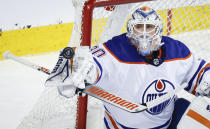 Edmonton Oilers goalie Calvin Pickard swats away a Calgary Flames shot during the first period of an NHL hockey game Saturday, April 6, 2024, in Calgary, Alberta. (Jeff McIntosh/The Canadian Press via AP)