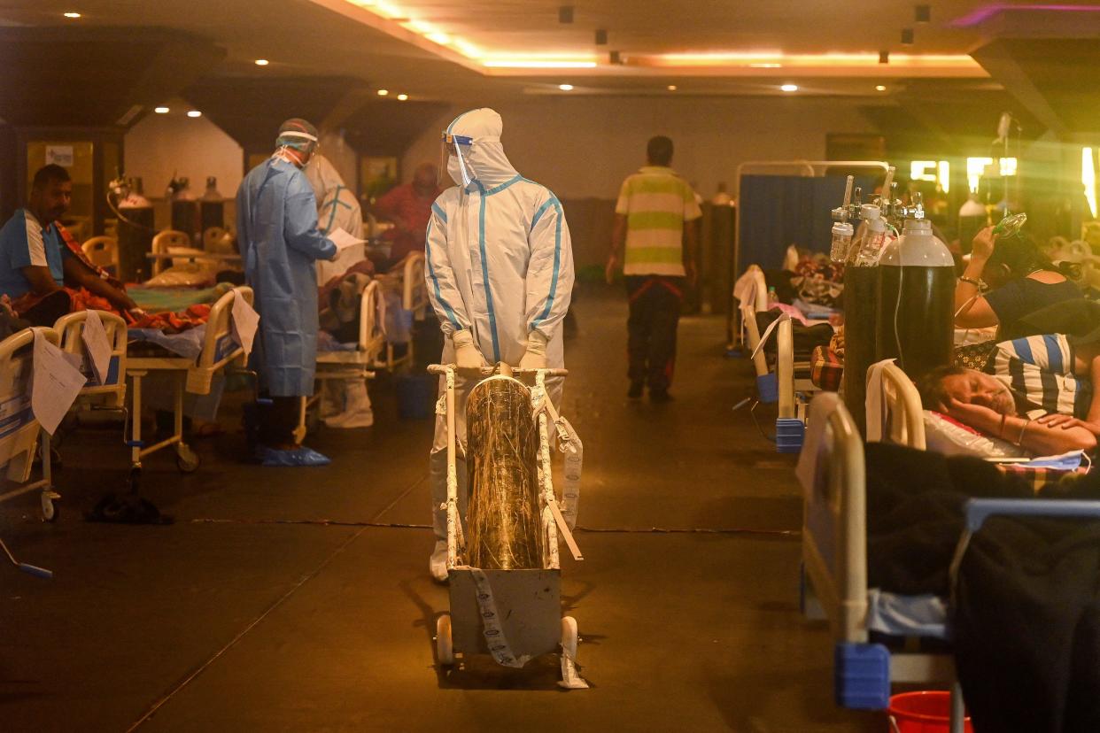 TOPSHOT - Health workers wearing personal protective equipment (PPE kit) attends to Covid-19 coronavirus positive patients inside a banquet hall temporarily converted into a covid care centre in New Delhi on April 28, 2021. (Photo by Prakash SINGH / AFP) (Photo by PRAKASH SINGH/AFP via Getty Images)