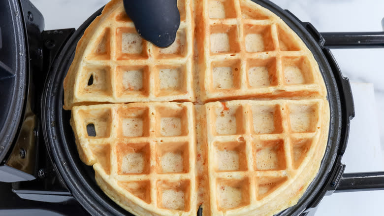 tongs pulling waffle from iron