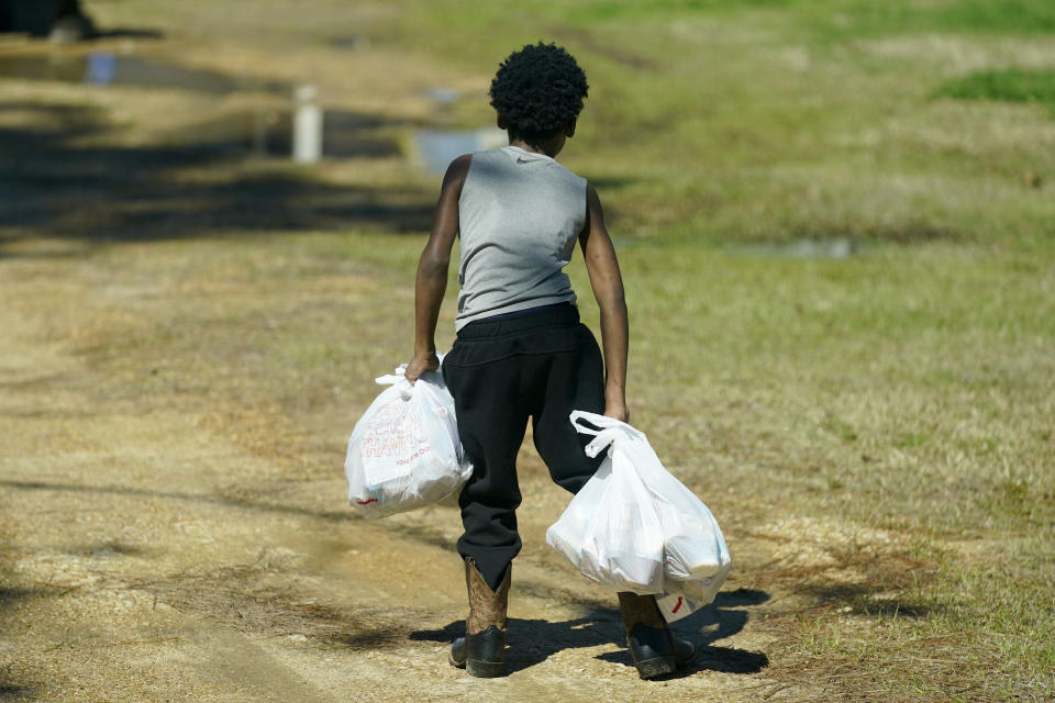 A Jefferson County student carries several days of breakfasts and lunches back to his home, March 3, 2021 in Fayette, Miss. As one of the nation's most food insecure counties, many families and their children come to depend on the free meals provided at school or delivered to their homes if they are virtually learning students, as their only means of daily sustenance. (AP Photo/Rogelio V. Solis)