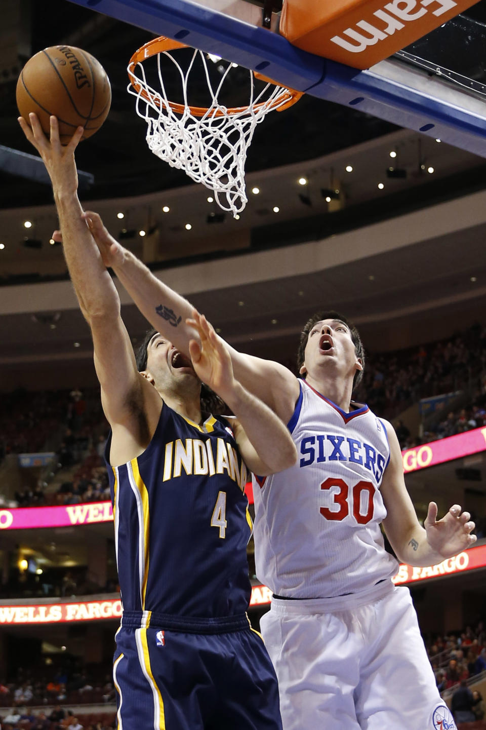 Indiana Pacers' Luis Scola, left, goes up to shoot against Philadelphia 76ers' Byron Mullens during the first half of an NBA basketball game on Friday, March 14, 2014, in Philadelphia. (AP Photo/Matt Slocum)