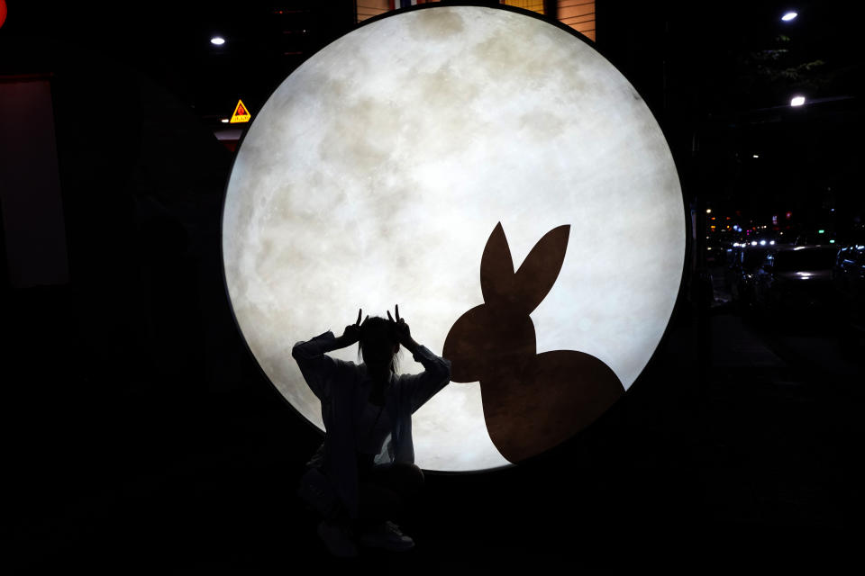 A Chinese tourist Niu Jiayi poses for picture near a light sculpture of Year of Rabbit in Bangkok, Thailand on Jan. 20, 2023. The expected resumption of group tours from China is likely to bring far more visitors. (AP Photo/Sakchai Lalit)