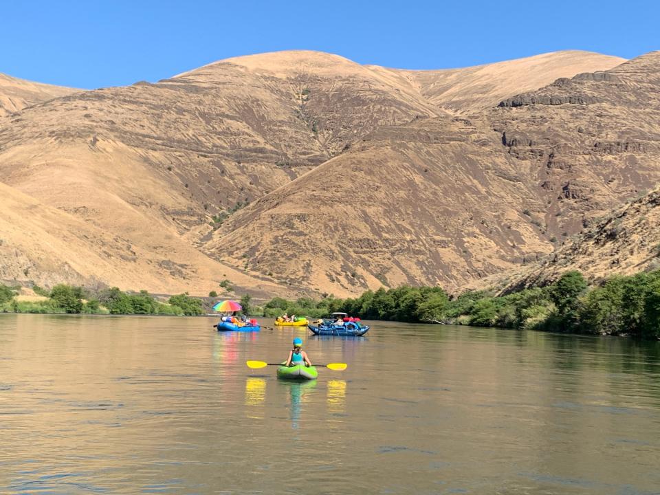 Rafters float down the Lower Deschutes River in a big desert canyon.