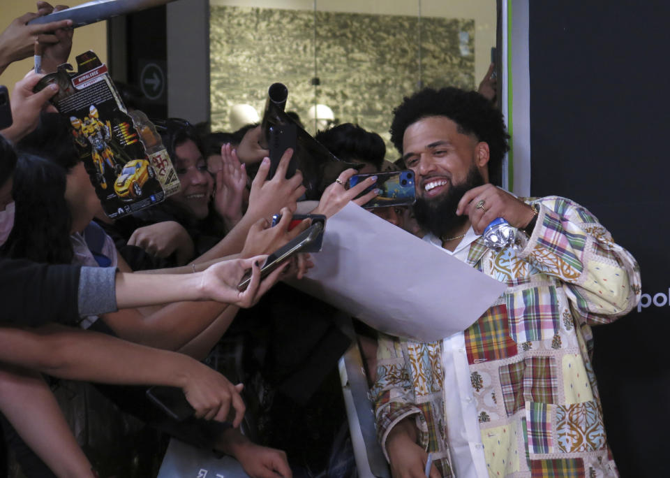 El director Steven Caple Jr. saluda a fans a su llegada a la alfombra roja de "Transformers: Rise of the Beasts", en la Ciudad de México el 30 de mayo de 2023. (Foto AP/Berenice Bautista)