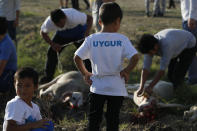 In this Aug. 21, 2018, photo, members of the Uighur community watch as others slaughter sheep following prayers at the start of the Eid al-Adha, or "Feast of Sacrifice," a feast celebrated by Muslims worldwide in Istanbul, Turkey. Muslims around the world celebrate Eid al-Adha, by sacrificing animals to commemorate the prophet Ibrahim's faith in being willing to sacrifice his son. Some of the meat is being given as aid to the poor and children also receive toys and money from their elders. (AP Photo/Lefteris Pitarakis)