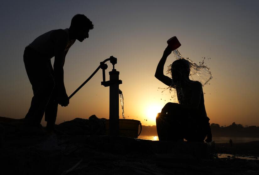 A Pakistani youth, right, cools off under a hand pump at sunset during hot weather in Lahore, Pakistan, Tuesday, May 28, 2024. (AP Photo/K.M. Chaudary)