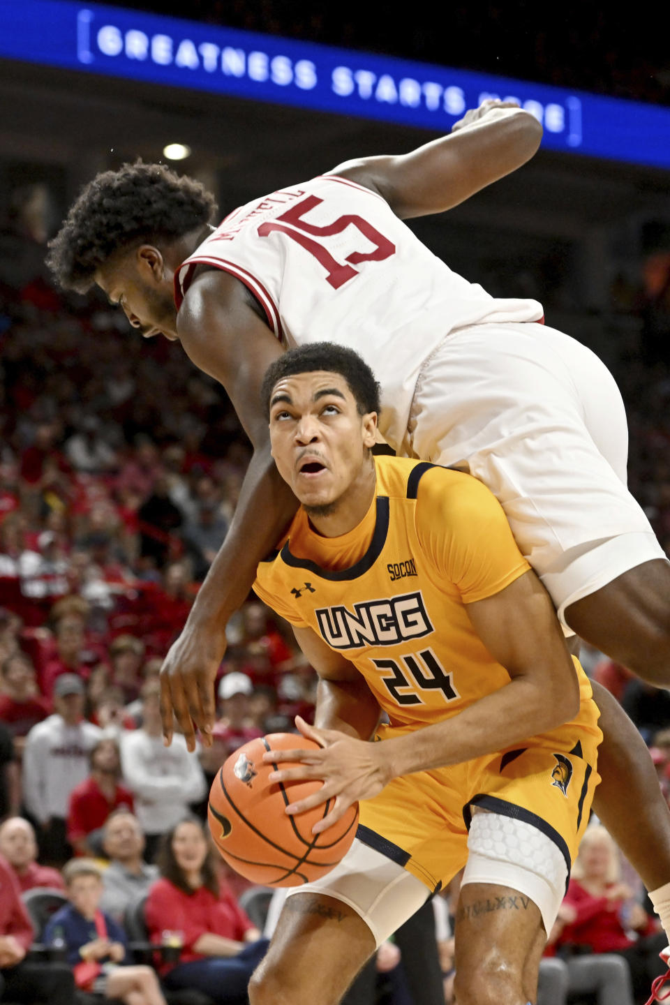 UNC Greensboro forward Tim Ceaser (24) is fouled by Arkansas forward Makhi Mitchell (15) as he drives to the hoop during the first half of an NCAA college basketball game Friday, Nov. 17, 2023, in Fayetteville, Ark. (AP Photo/Michael Woods)