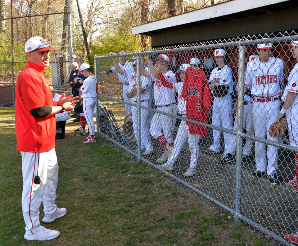 The Holliston High School baseball team hangs a No. 20 jersey in honor of Holliston alum Corey Ciarcello (‘09) who died in February, here at their game against Dover-Sherborn on May 11. Coach Joe Santos, left, played with Ciarcello.