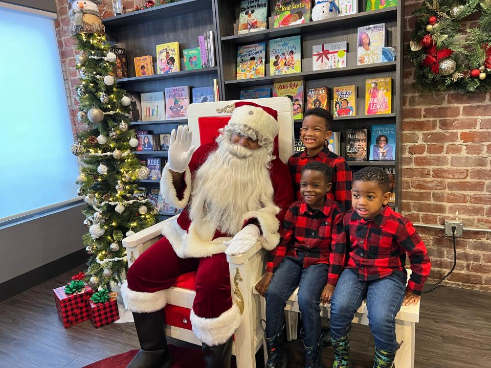 Black Santa poses for a family photo on Dec. 10, 2022, at Underground Books in Sacramento, California, as part of community nonprofit St. HOPE's annual holiday celebrations.