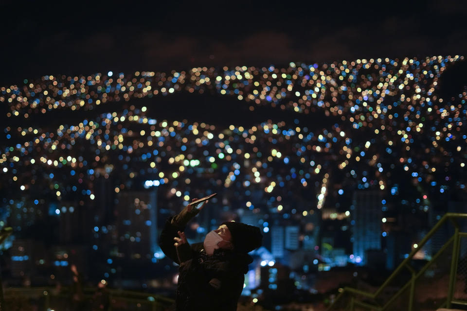 A woman takes a photo of the first blood moon lunar eclipse of the year at the Killi Killi lookout in La Paz, Bolivia, Sunday, May 15, 2022. (AP Photo/Juan Karita)