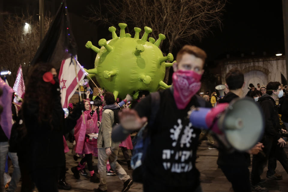 Israeli protesters march with a large inflatable model of the coronavirus on their way to Israeli Prime Minister Benjamin Netanyahu's official residence in Jerusalem, Saturday, Feb. 6, 2021. (AP Photo/Maya Alleruzzo)