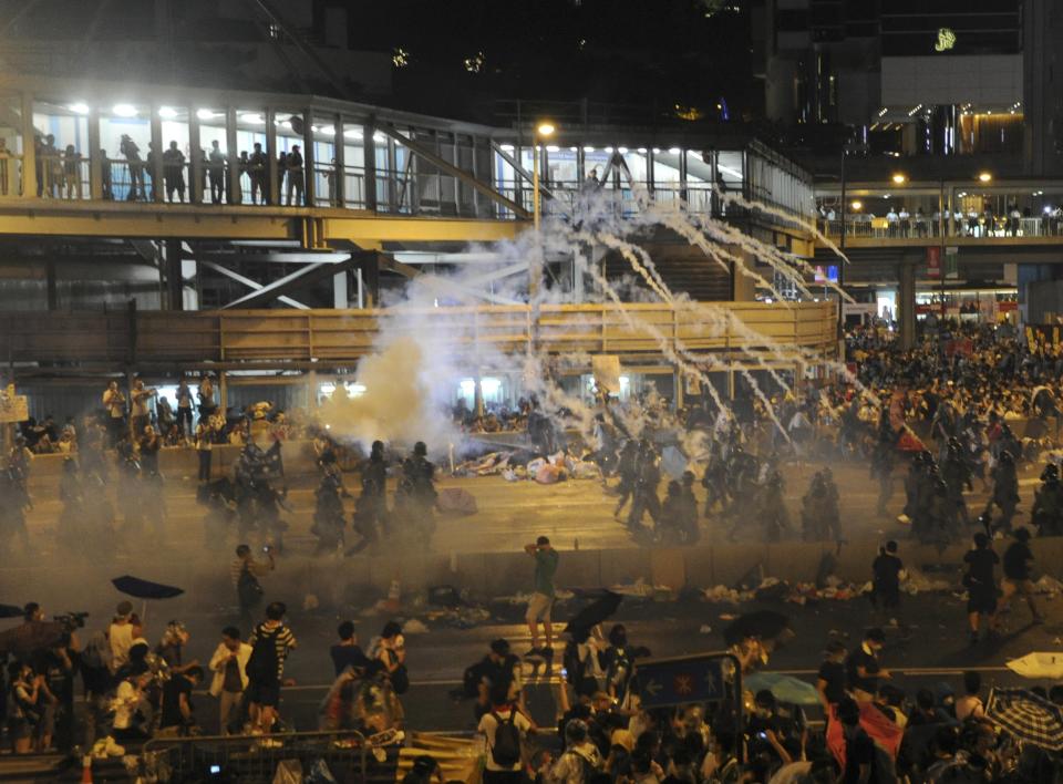 Riot police fire teargas to disperse protesters, after thousands of protesters blocked the main street to the financial Central district outside the government headquarters in Hong Kong September 28, 2014. Hong Kong police fired repeated volleys of tear gas to disperse pro-democracy protests on Sunday and baton-charged the crowd blocking a key road in the government district after official warnings against illegal demonstrations. REUTERS/Stringer (CHINA - Tags: POLITICS CIVIL UNREST) HONG KONG OUT. NO COMMERCIAL OR EDITORIAL SALES IN HONG KONG