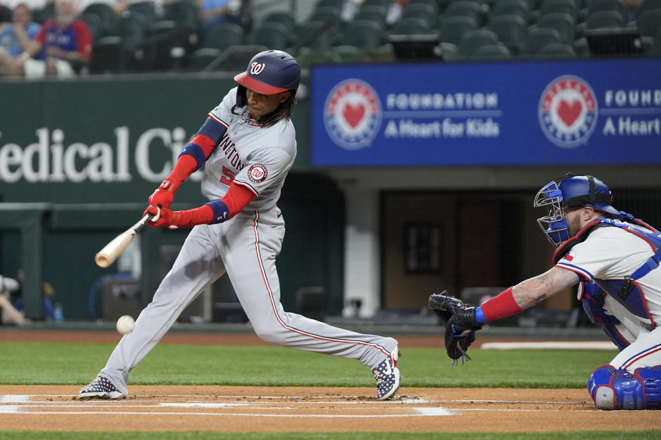 Washington Nationals shortstop CJ Abrams connects for a single as Texas Rangers catcher Jonah Heim looks on in the first inning of a baseball game in Arlington, Texas, Tuesday, April 30, 2024. (AP Photo/Tony Gutierrez)