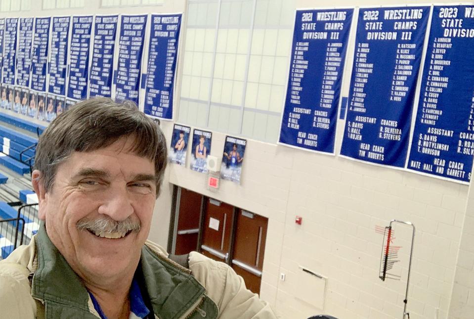 Photographer Tom Hawley takes a selphie with the Dundee championship banners that hang in the gym at the high school.