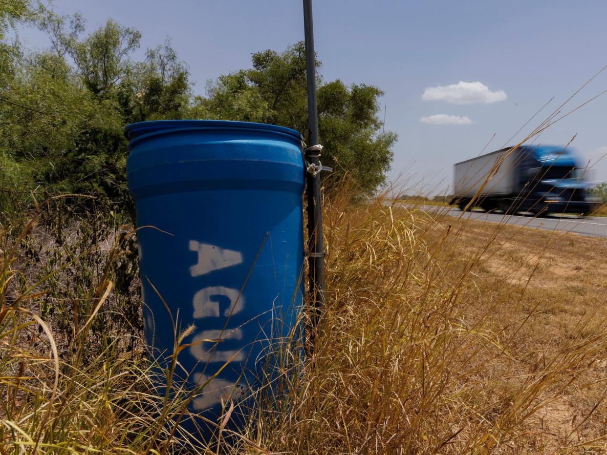 A water station for immigrants containing sealed jugs of fresh water sits along a fence line near a roadway in rural Jim Hogg County, Texas, Tuesday, July 25, 2023.