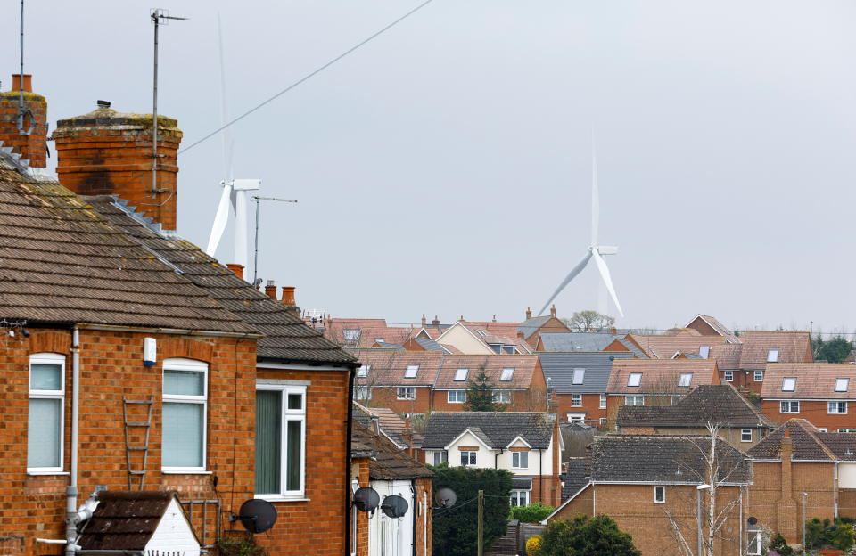 Tenants  Wind turbines are seen behind houses in Burton Latimer, Britain, March 30, 2022. REUTERS/Andrew Boyers