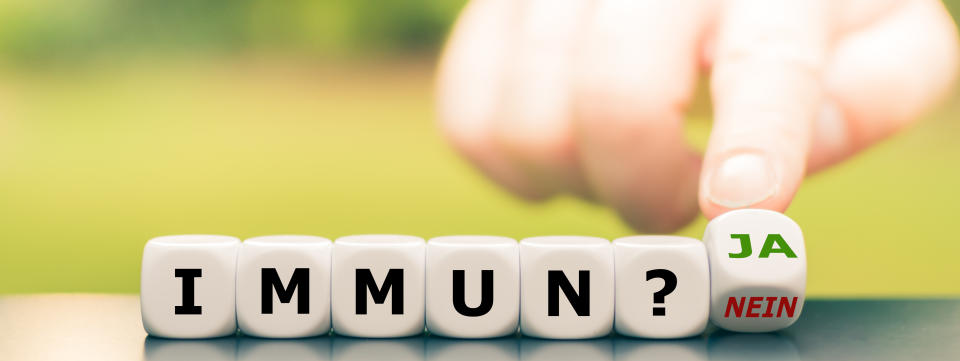 Corona immune? Hand turns dice and changes the German expression "immun? nein" ("immune? no") to "immun? ja" ("immune? yes").