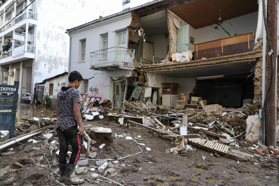 A boy stands in front of a building which partially collapsed after a storm at Karditsa town, Saturday, Sept. 19, 2020. Two people have died and one is reported missing in the central Greek region of Thessaly as a rainstorm pounded parts of central and western Greece overninght and caused rivers to burst their banks and flood surrounding areas. (AP Photo/Vaggelis Kousioras)