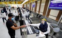 Passengers wearing protective masks check-in after the reopening of Baghdad International Airport, where flights halted due to the coronavirus disease (COVID-19) outbreak, in Baghdad