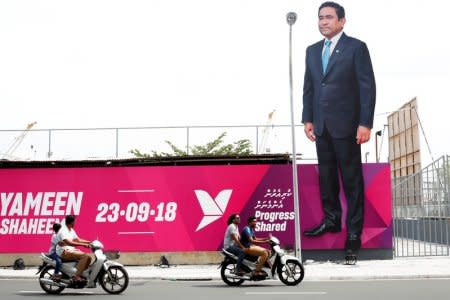 FILE PHOTO: People ride motorcycles past an image of Maldives President Abdulla Yameen on a road ahead of the presidential election in Male, Maldives September 19, 2018. REUTERS/Ashwa Faheem