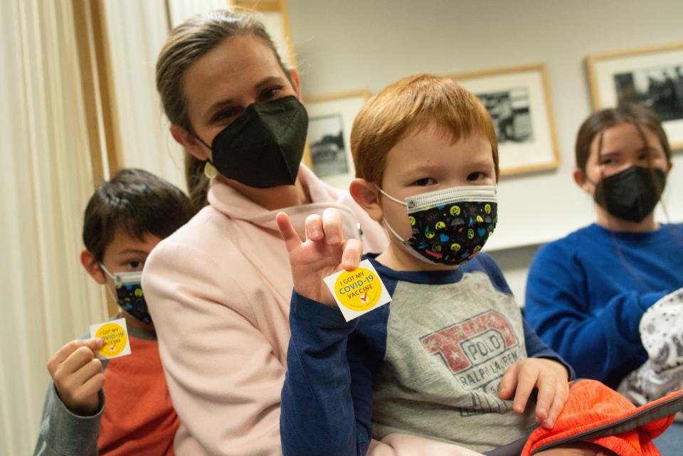 7-year-old Jack Carlson, middle, holds up a vaccine sticker along with siblings Brantley Carlson, 9, and Amelia Carlson, 11, while at a vaccine clinic Thursday morning with their mother, Amber Carlson. All three children got their first dose of the Pfizer COVID-19 pediatric vaccine becoming some of the first kids in Topeka to receive the vaccine after it became available for their age group. (Via OlyDrop)