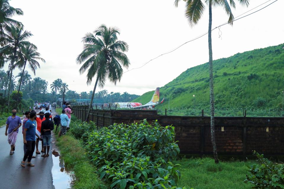 People gather near the wreckage of an Air India Express jet at Calicut International Airport in Karipur, Kerala, on August 8, 2020. - Fierce rain and winds lashed a plane carrying 190 people before it crash-landed and tore in two at an airport in southern India, killing at least 18 people and injuring scores more, officials said on August 8. (Photo by Arunchandra BOSE / AFP) (Photo by ARUNCHANDRA BOSE/AFP via Getty Images)