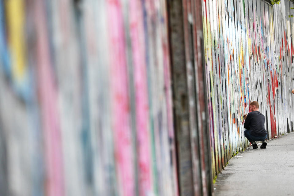 A tourist signs the “peace walls” that still separate some nationalist and unionist neighborhoods in west Belfast, Northern Ireland, Wednesday, April 5, 2023. It has been 25 years since the Good Friday Agreement largely ended a conflict in Northern Ireland that left 3,600 people dead. (AP Photo/Peter Morrison)