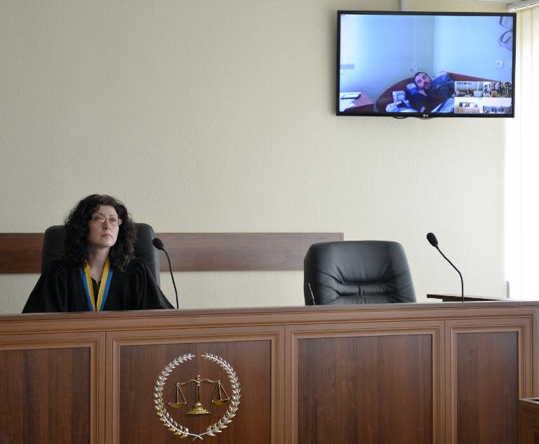 A judge of Kiev's district court (L) listens to one of the two captured Russian soldiers participating in the trial by videoconference on May 22, 2015