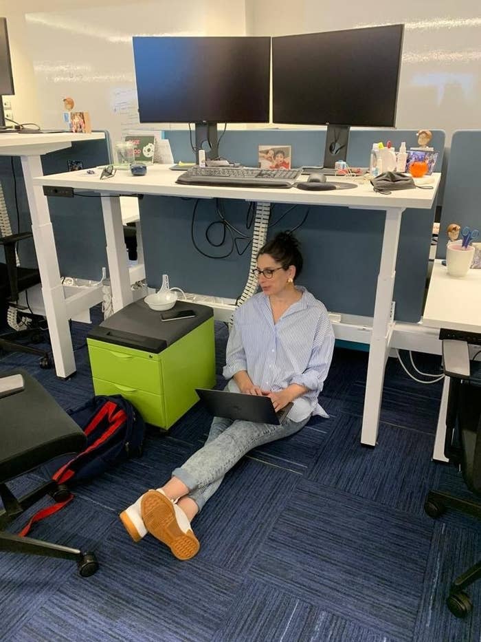 Minnie sitting under her desk with her laptop, getting work done