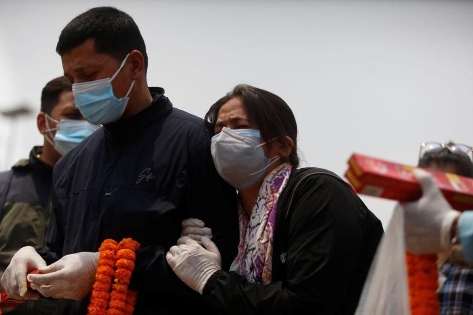 A woman and a man mourn for a family member who died from the COVID-19 in Kathmandu, Nepal