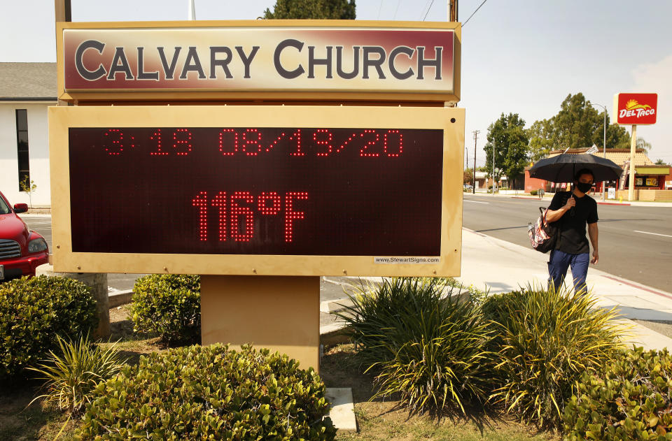 A man with an umbrella for shade walks past the thermometer at Calvary Church in Woodland Hills, California, as it registers 116 degrees Fahrenheit on Aug. 19. (Photo: Al Seib via Getty Images)