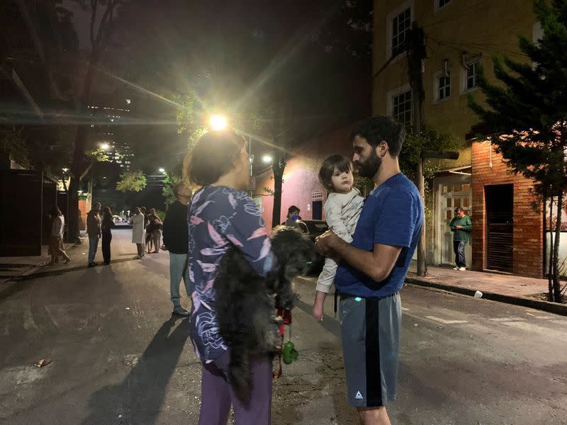 People wait outside their homes after a tremor was felt in Mexico City