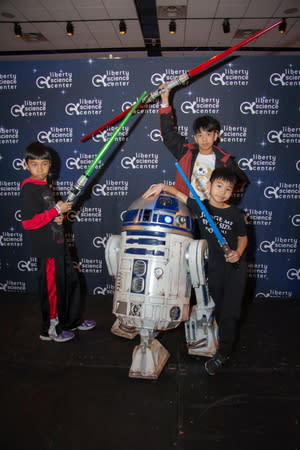 Visitors pose with R2-D2 Feb.12 at Liberty Science Center's "Science, Sabers & Star Wars" event. 