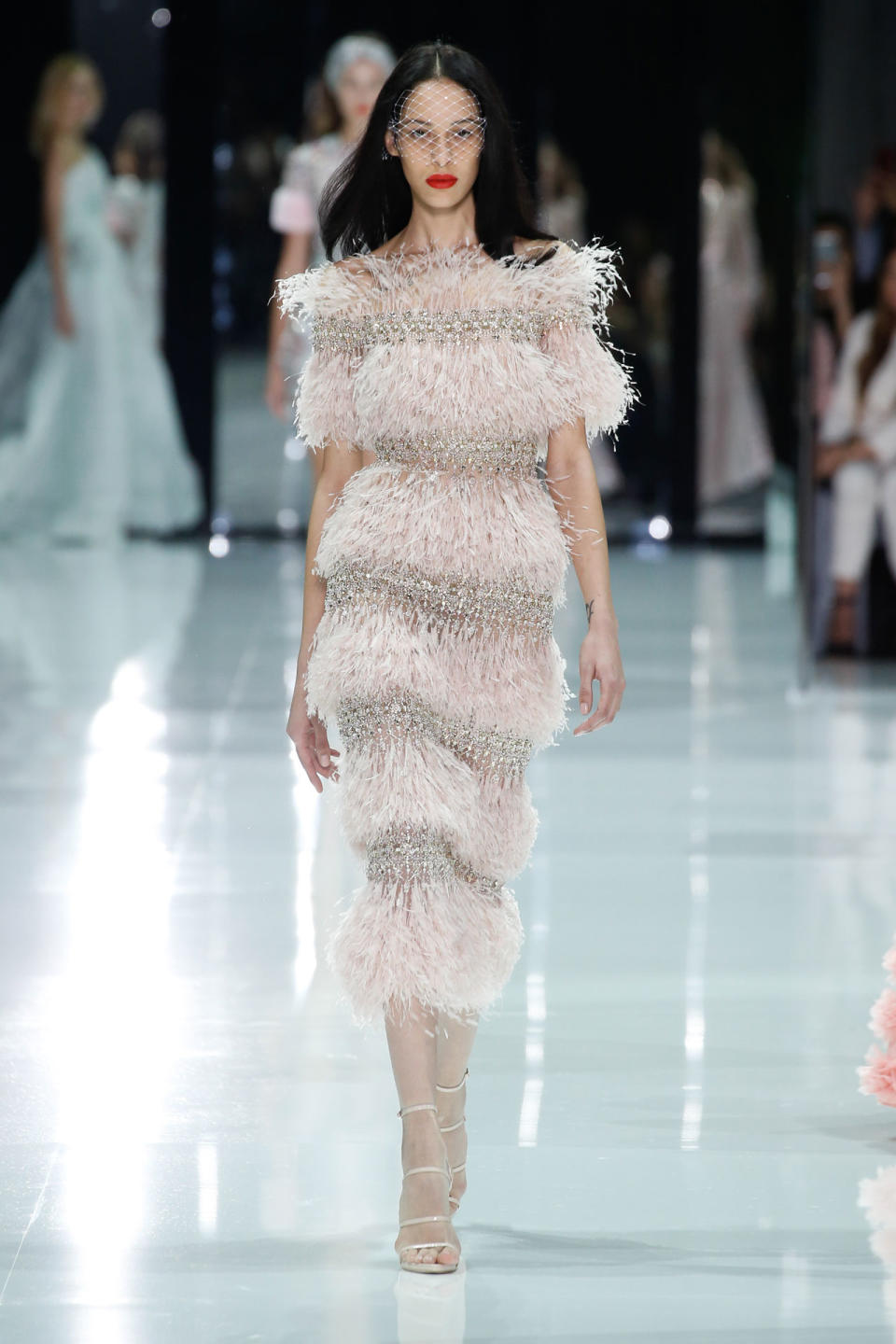 <p>Ein Model trägt bei der Ralph & Russo Frühjahr/Sommer 18 Haute Couture Modenschau ein gestuftes pinkes Kleid mit Federn und Kristallen. (Bild: Getty Images) </p>