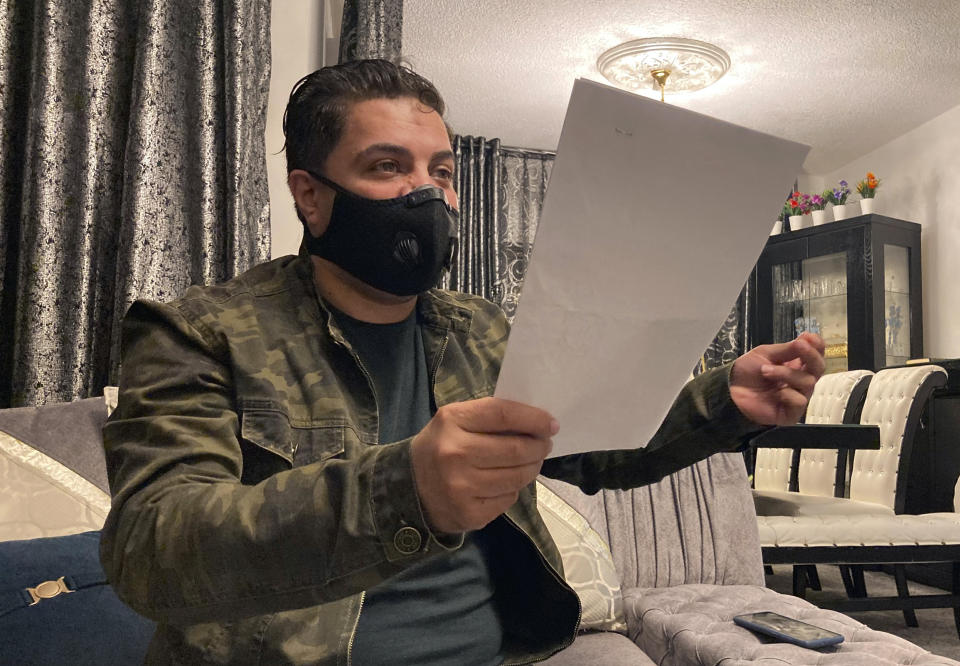 Samer Qraih, a Jordanian car dealer, sits in his apartment holding old business licences, bank statements and documents, in Amman, Jordan, Sunday, March 14, 2021. The 45-year-old, and father of four was sent to nine months in prison after he sank in into massive debts. Hundreds of thousands of Jordanians like Qraih are faced with incarceration because of draconian debt laws that violate international human rights law, according to the report published Tuesday by Human Rights Watch. (AP Photo/Omar Akour)