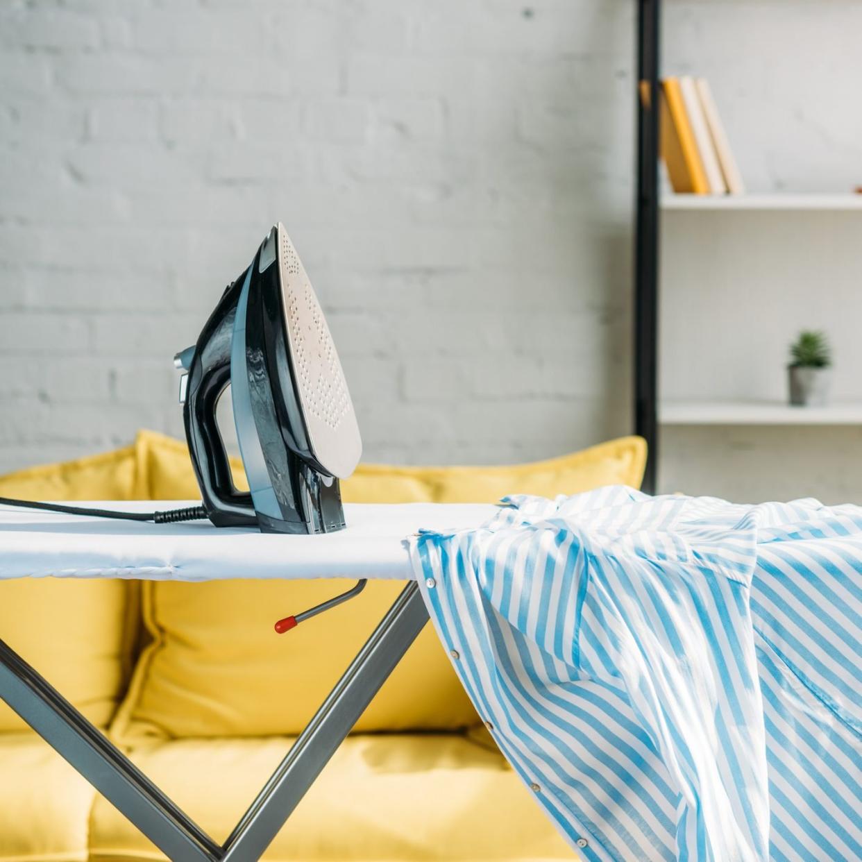 striped blue shirt and iron on ironing board at home