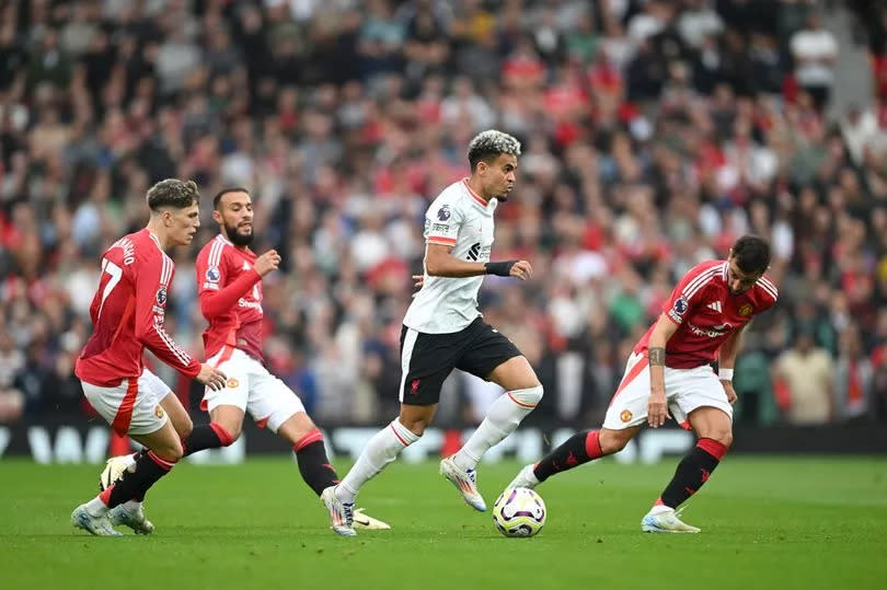 Luis Diaz of Liverpool runs with the ball under pressure from Alejandro Garnacho and Bruno Fernandes of Manchester United