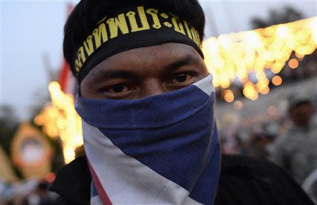 An anti-government protester, wearing a face mask in Thai national colours, rests as they tear down barricades during a demonstration outside Government House in Bangkok November 30, 2013. REUTERS/Dylan Martinez