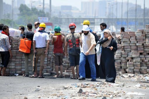 A couple walk past Muslim Brotherhood members at a makeshift barricade in Nasr City, eastern Cairo, on Sunday. Sporadic violence was reported in several towns early on Sunday, with two dead in separate incidents