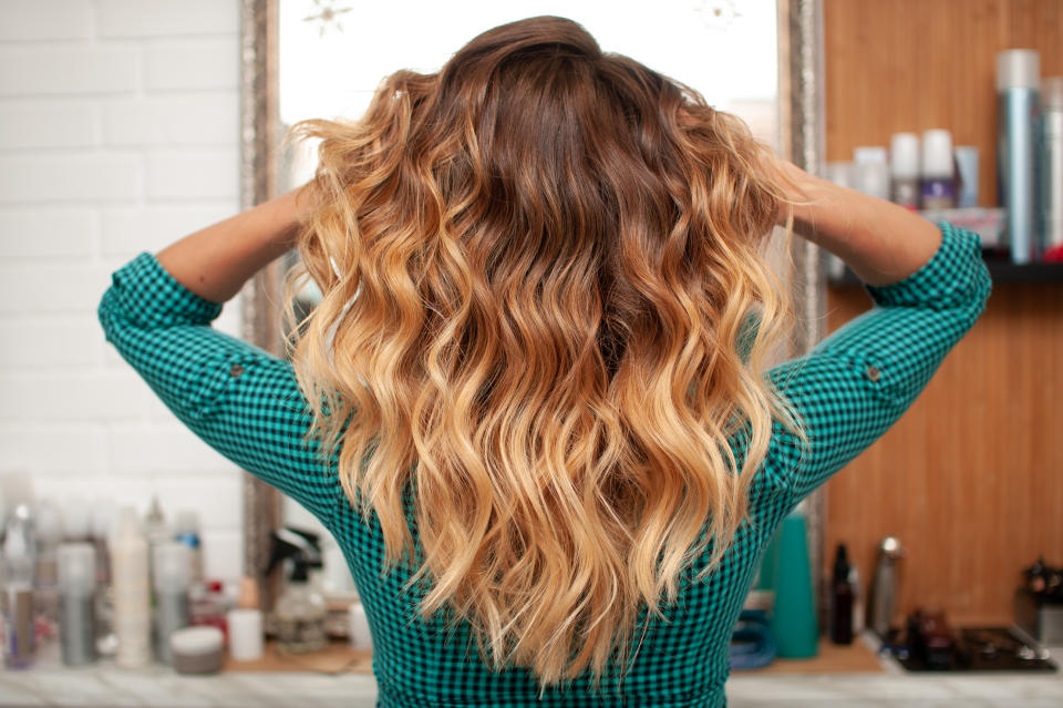 Hair coloring gradient from light golden to brown on a girl with long curly hair in the back