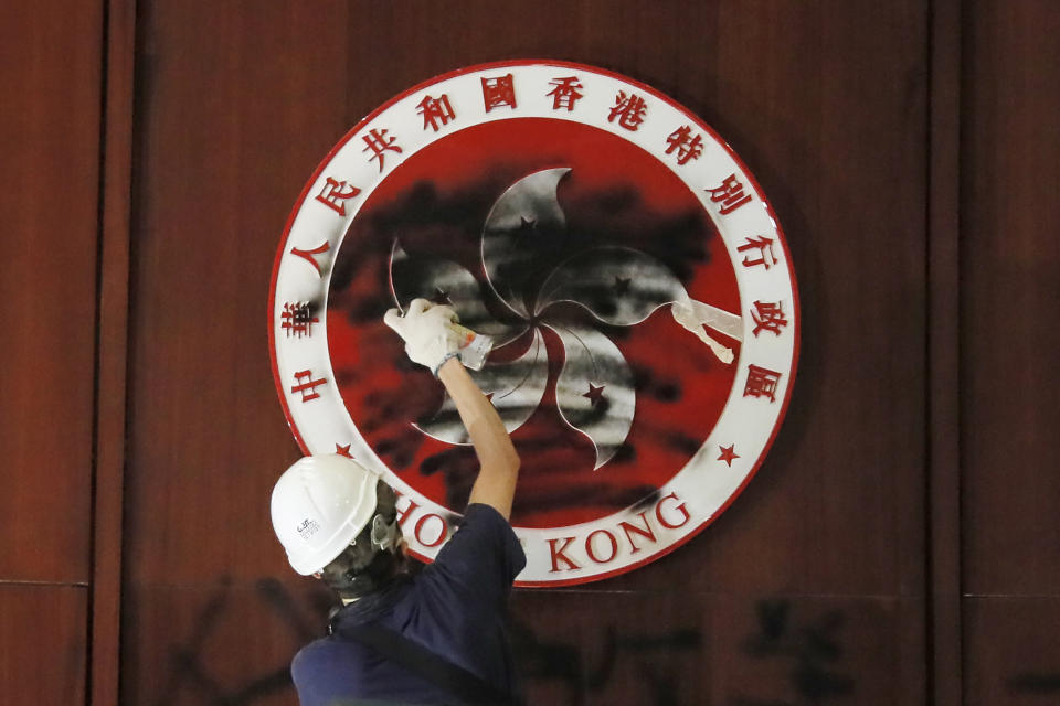 A protester defaces the Hong Kong emblem after they broke into the Legislative Council building in Hong Kong, Monday, July 1, 2019. One year ago, a sea of humanity - a million people by some estimates - marched through central Hong Kong on a steamy afternoon. It was the start of what would grow into the longest-lasting and most violent anti-government movement the city has seen since its return to China in 1997. (AP Photo/Kin Cheung, File)