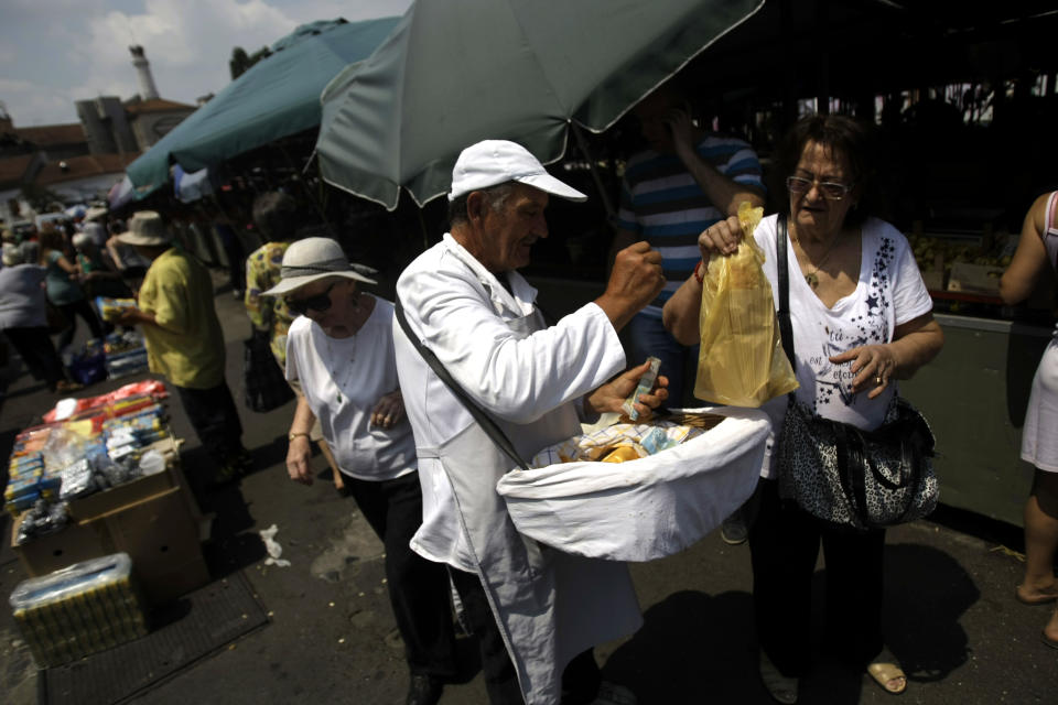 In this photo taken Thursday, July 11, 2013, a man sells bread at the Bajloni open green market in Belgrade, Serbia. Belgrade today is known for nightlife, clubbing and a fun-loving lifestyle, but its past is scarred by war. Over centuries it was conquered and demolished dozens of times, standing at the historic crossroads between two mighty empires, Turkish to the east and Austro-Hungarian to the west. But Belgrade’s citizens like to compare their city to the mythical phoenix bird that always rises from the ashes. (AP Photo/ Marko Drobnjakovic)