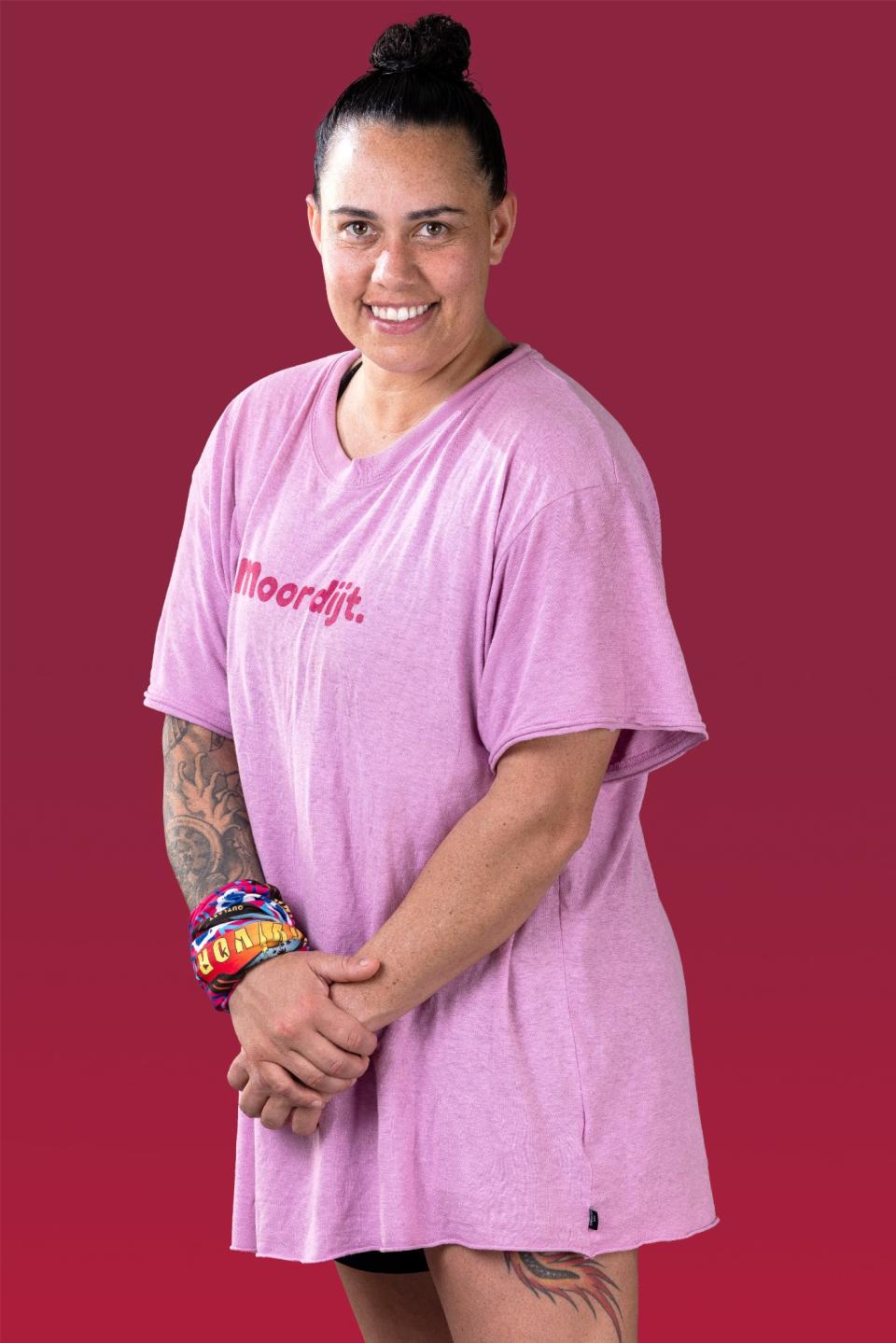 Kirby wears a pink t-shirt and smiles at the camera.